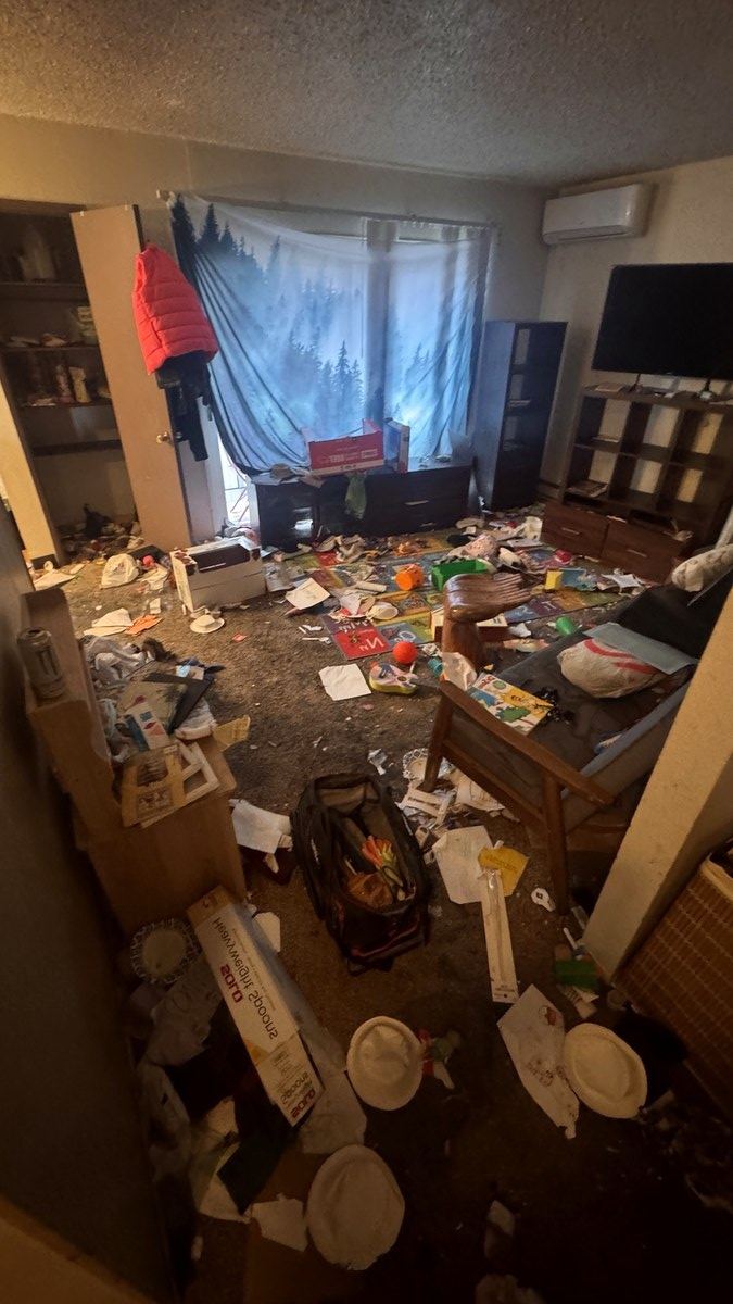 Living room before junk removal: packed with furniture, cardboard and debris